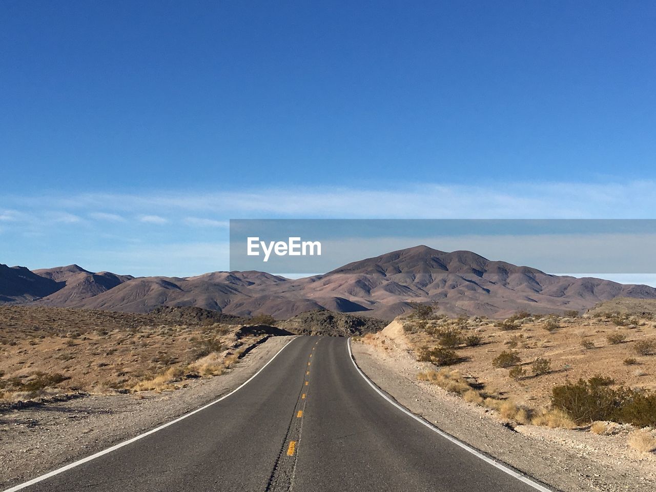 Empty road in desert against blue sky