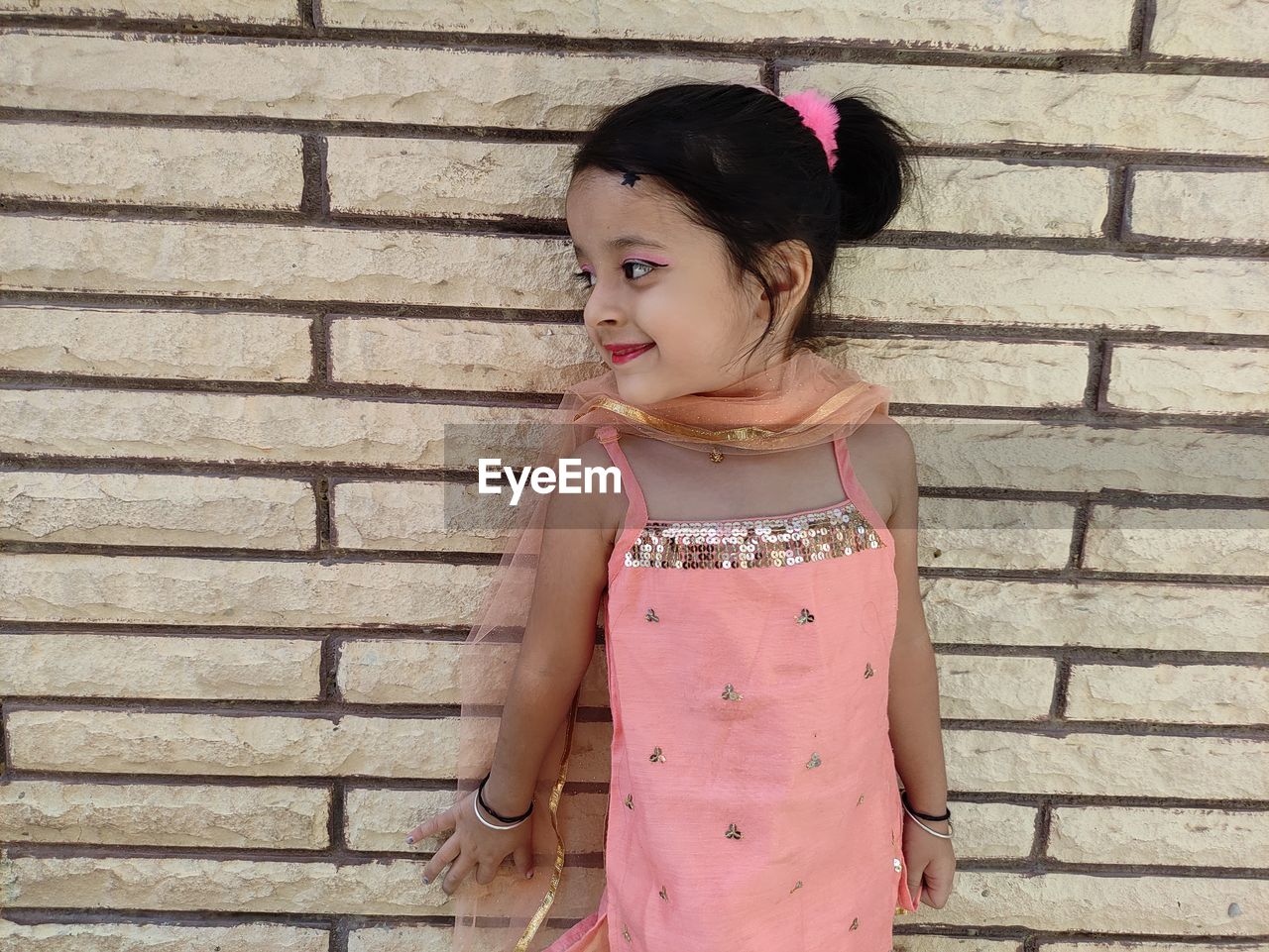 PORTRAIT OF A GIRL STANDING AGAINST WALL