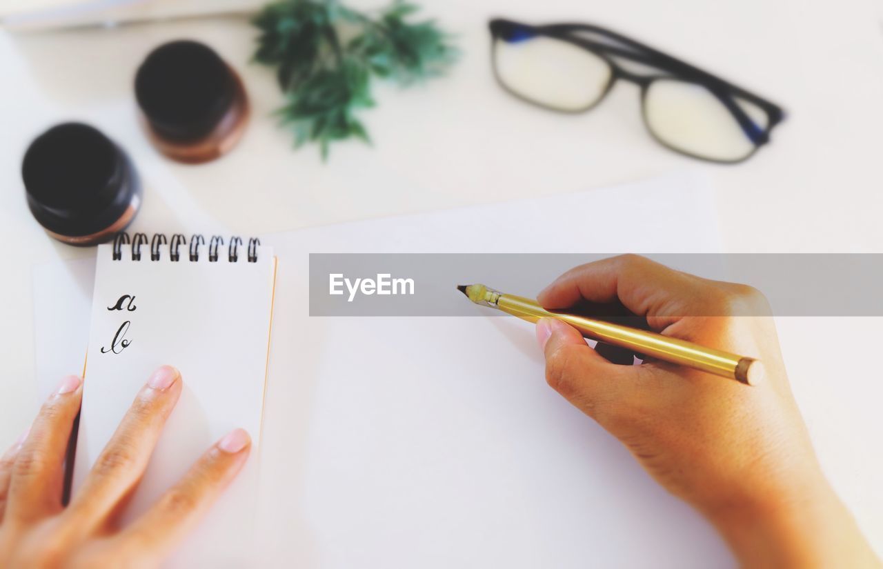 Calligraphy expert holding fountain pen over paper on table