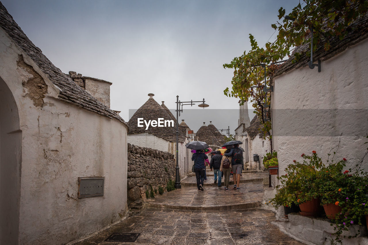 Tourists in the rain as they visit the streets of the alberobello village, italy