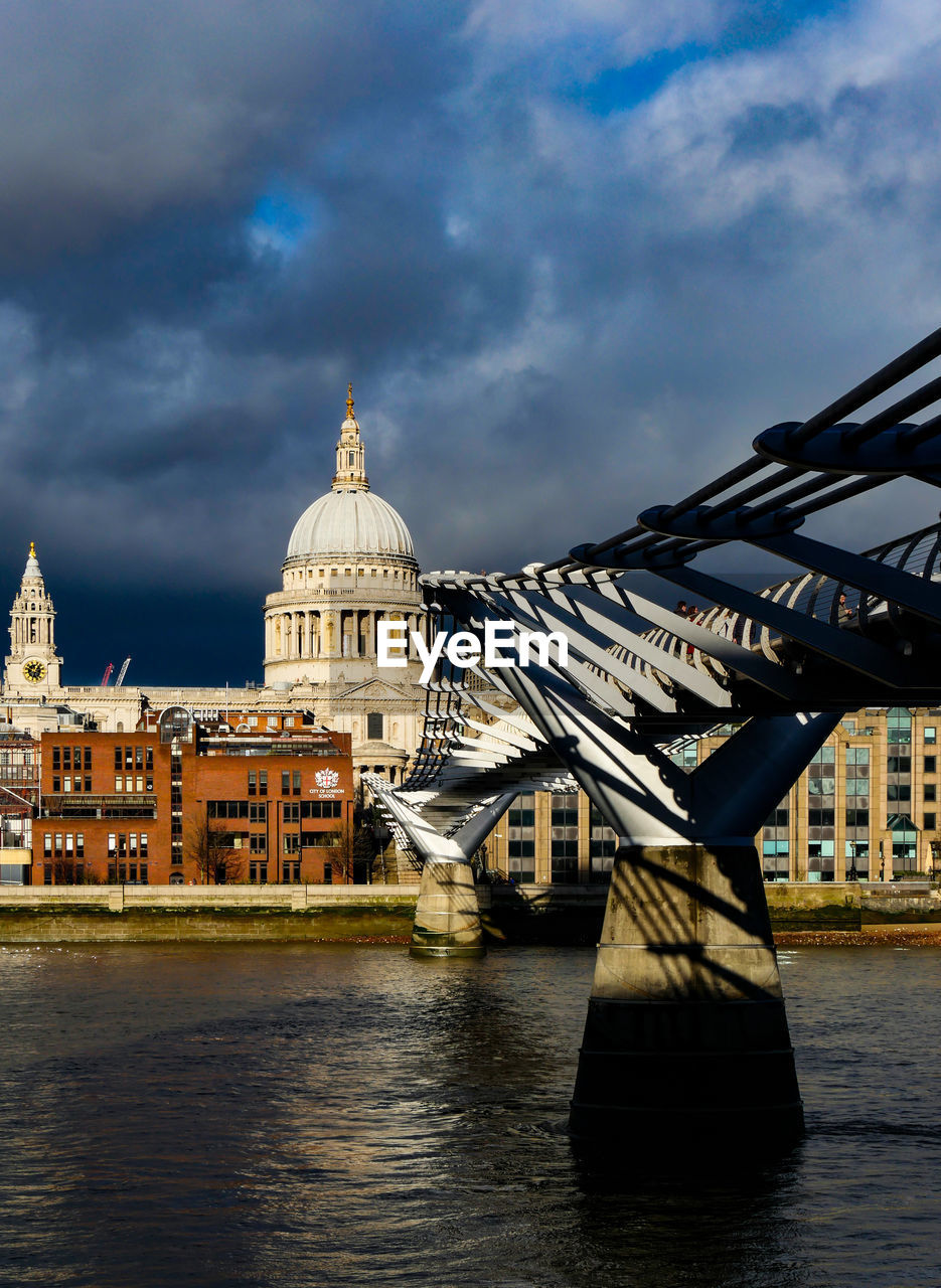 BRIDGE OVER RIVER BY BUILDINGS AGAINST SKY