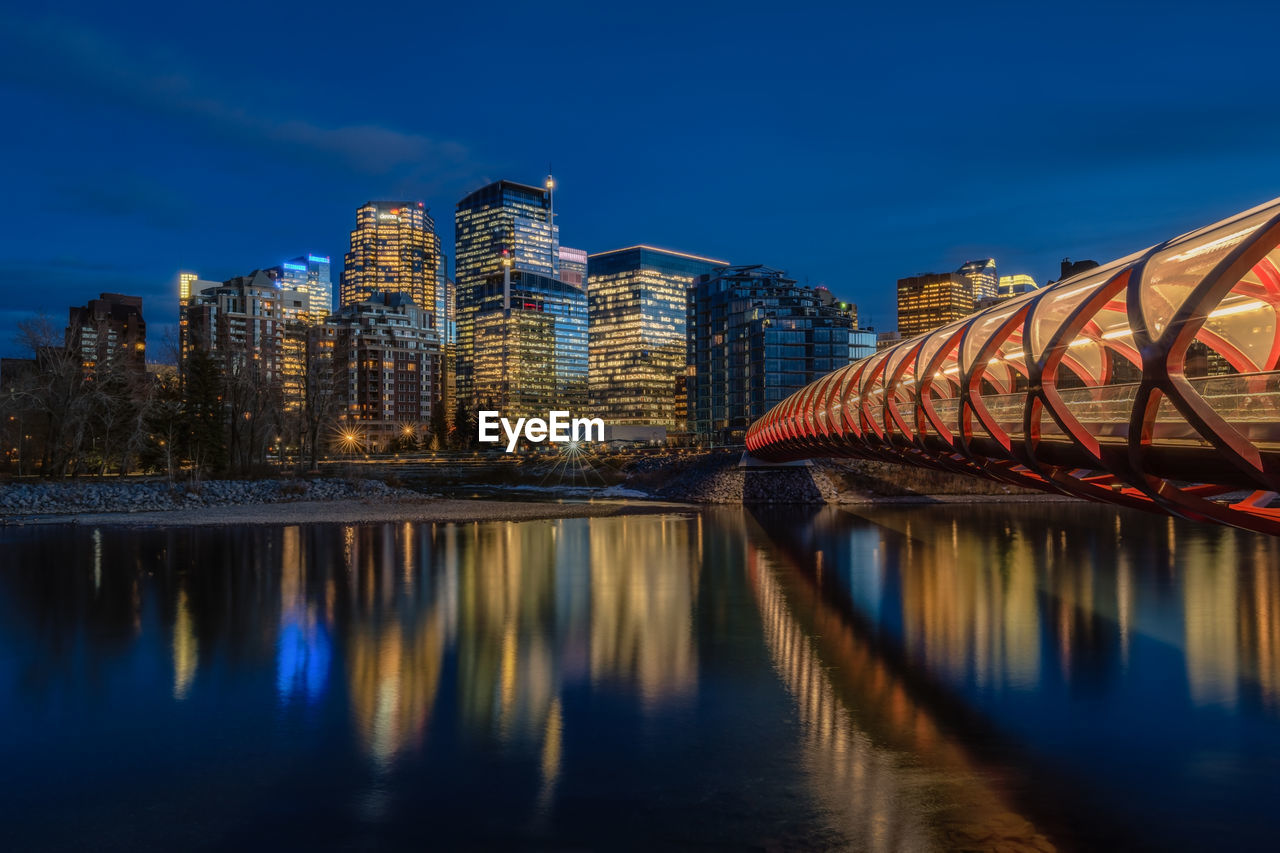 REFLECTION OF ILLUMINATED BUILDINGS ON RIVER AT NIGHT