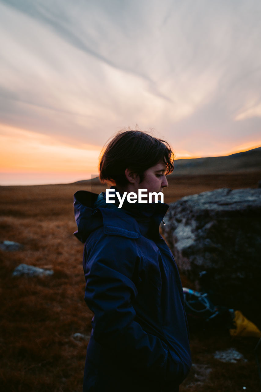 Man looking at sea shore against sky during sunset