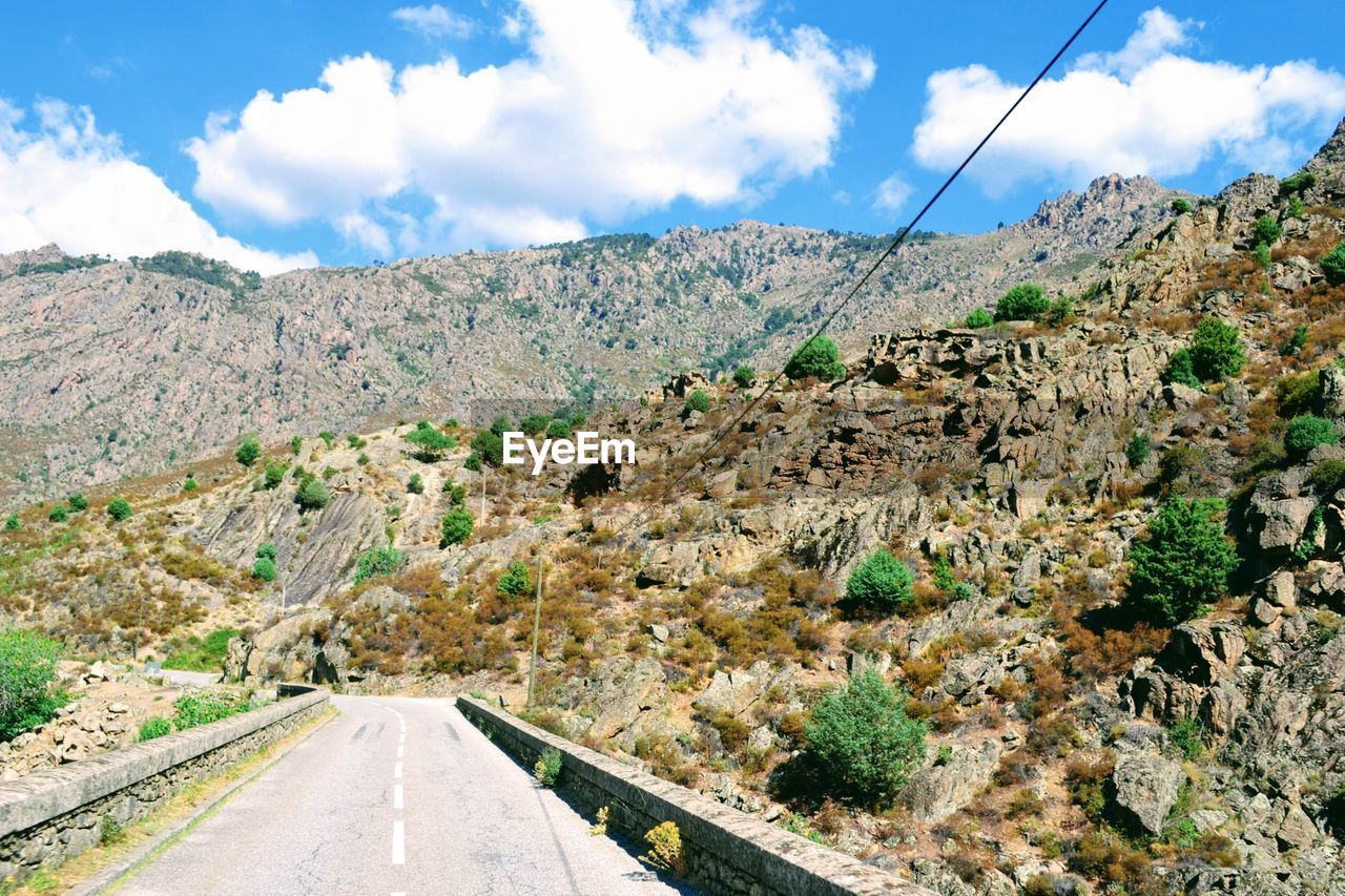 Scenic view of road by mountains against sky