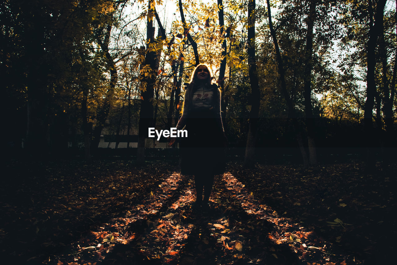 Woman standing against trees in park