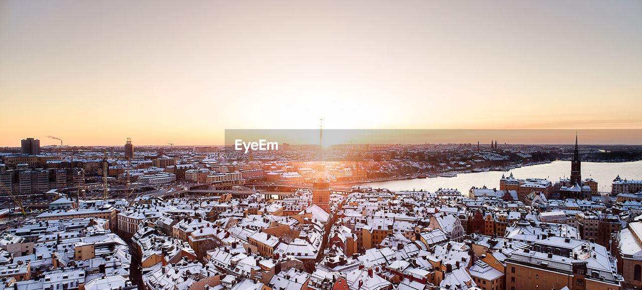 SNOW COVERED BUILDINGS AGAINST SKY DURING SUNSET IN WINTER