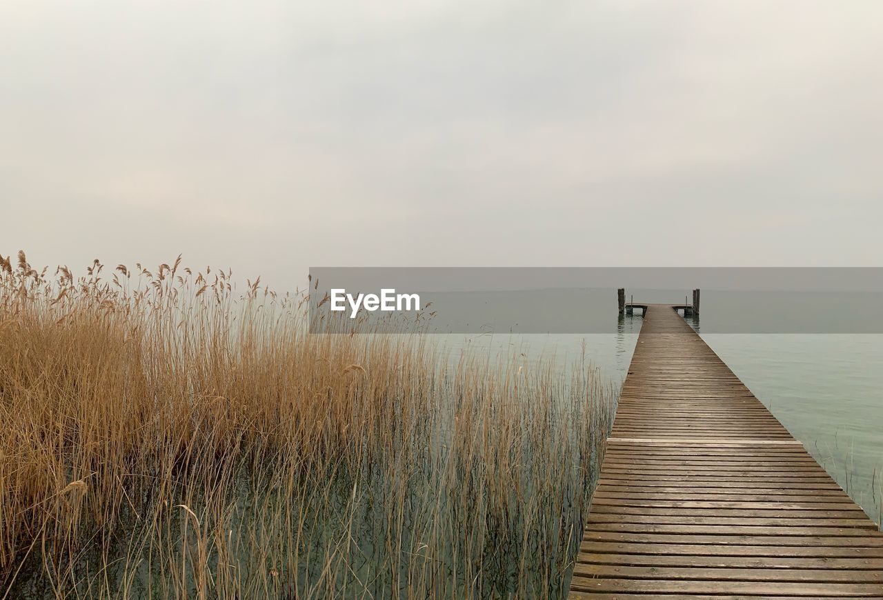 Wooden pier over sea against sky