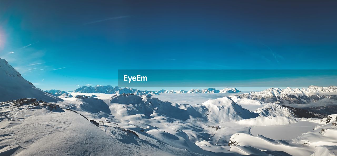 Scenic view of snowcapped mountains against blue sky