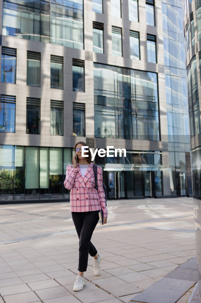 portrait of young woman standing against buildings