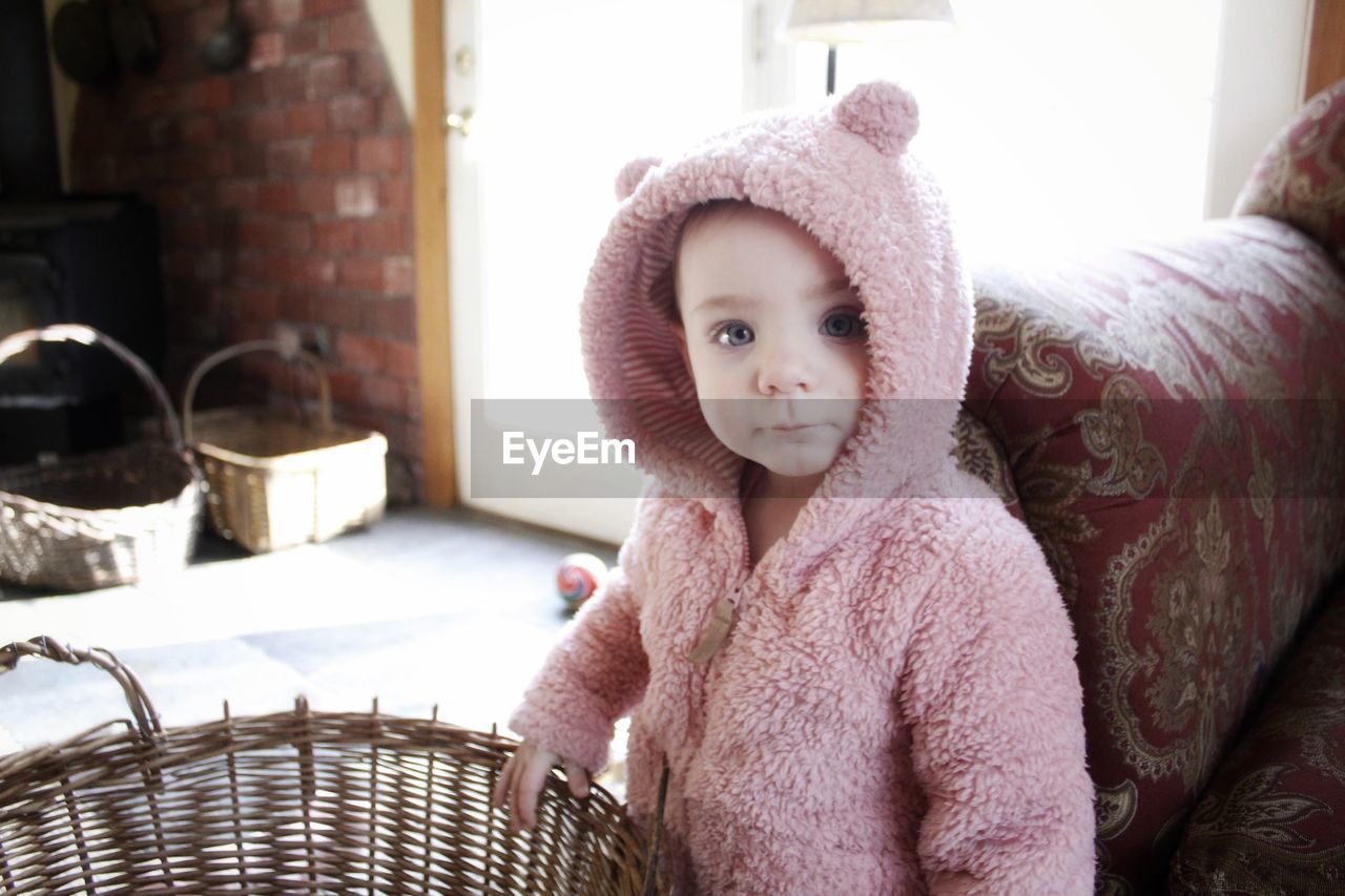 Portrait of cute baby girl in warm clothing standing at home