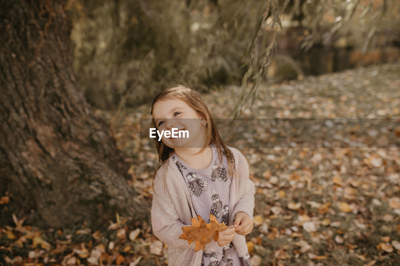 PORTRAIT OF SMILING GIRL STANDING ON LAND