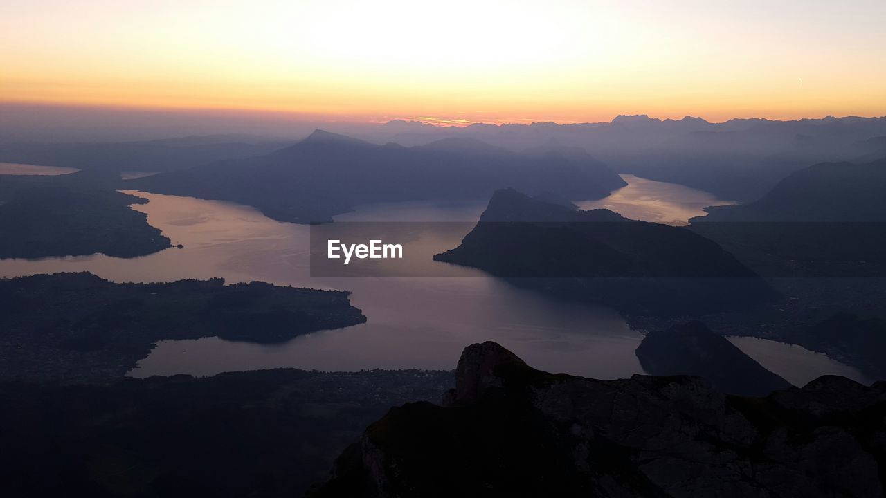 Scenic view of lake and mountains against sky during sunrise