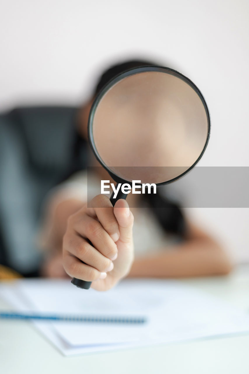 Girl holding magnifying glass on table