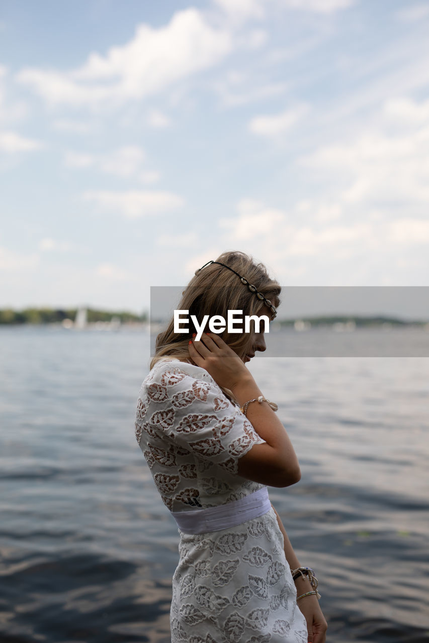 Woman standing by lake against sky