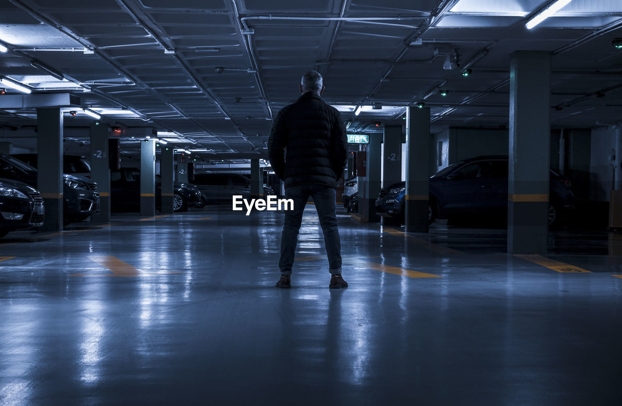 Rear view of adult man standing in underground parking lot. madrid, spain
