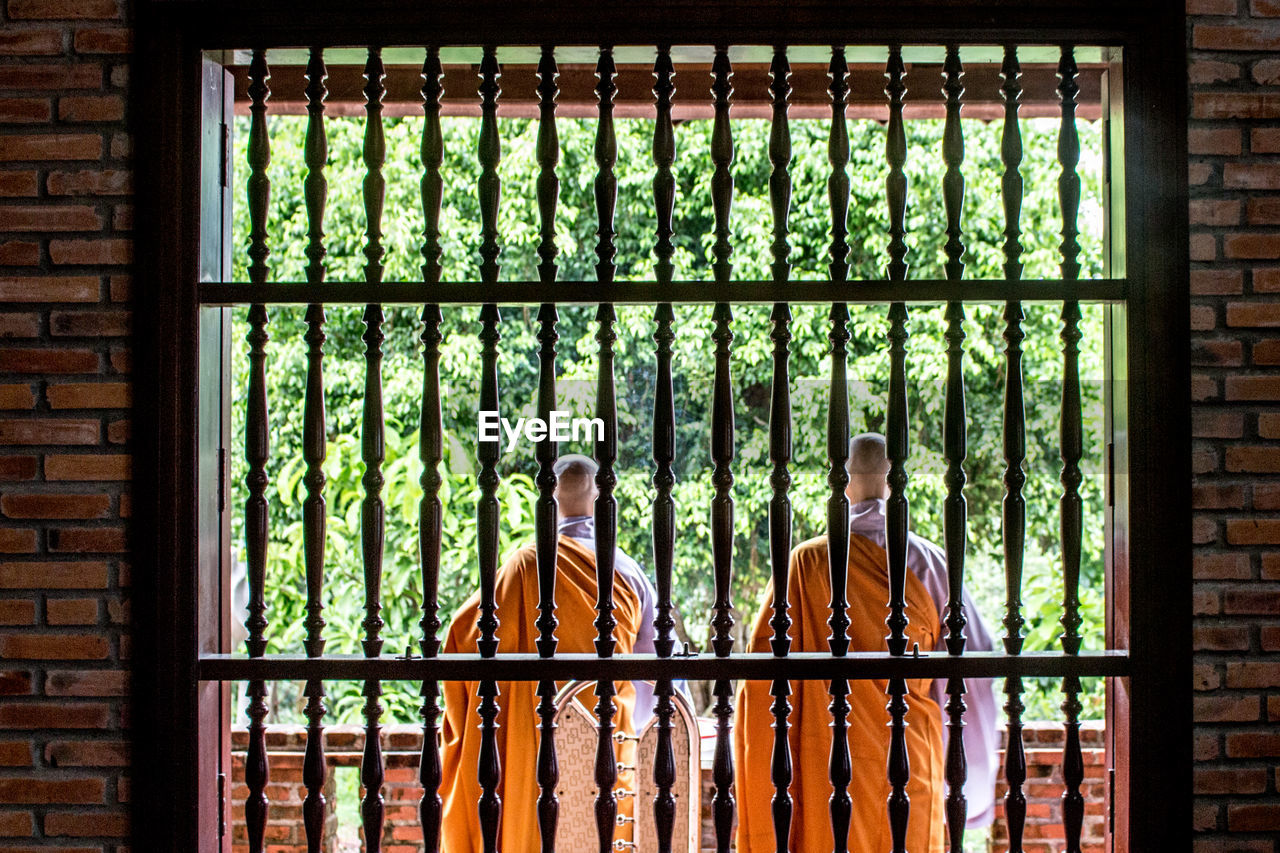 Rear view of monks seen through window at pagoda