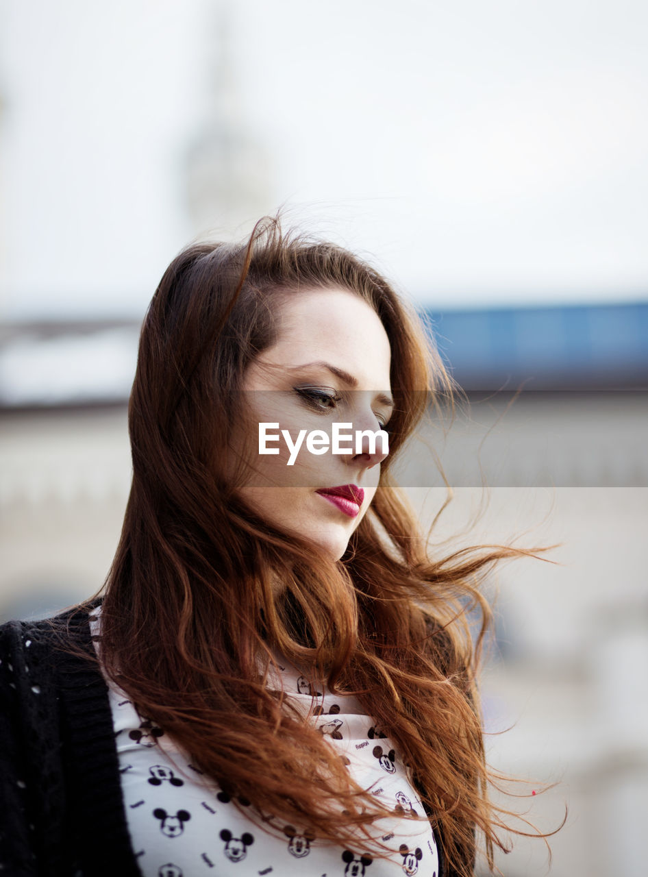 Portrait of beautiful young woman standing outdoors on the wind