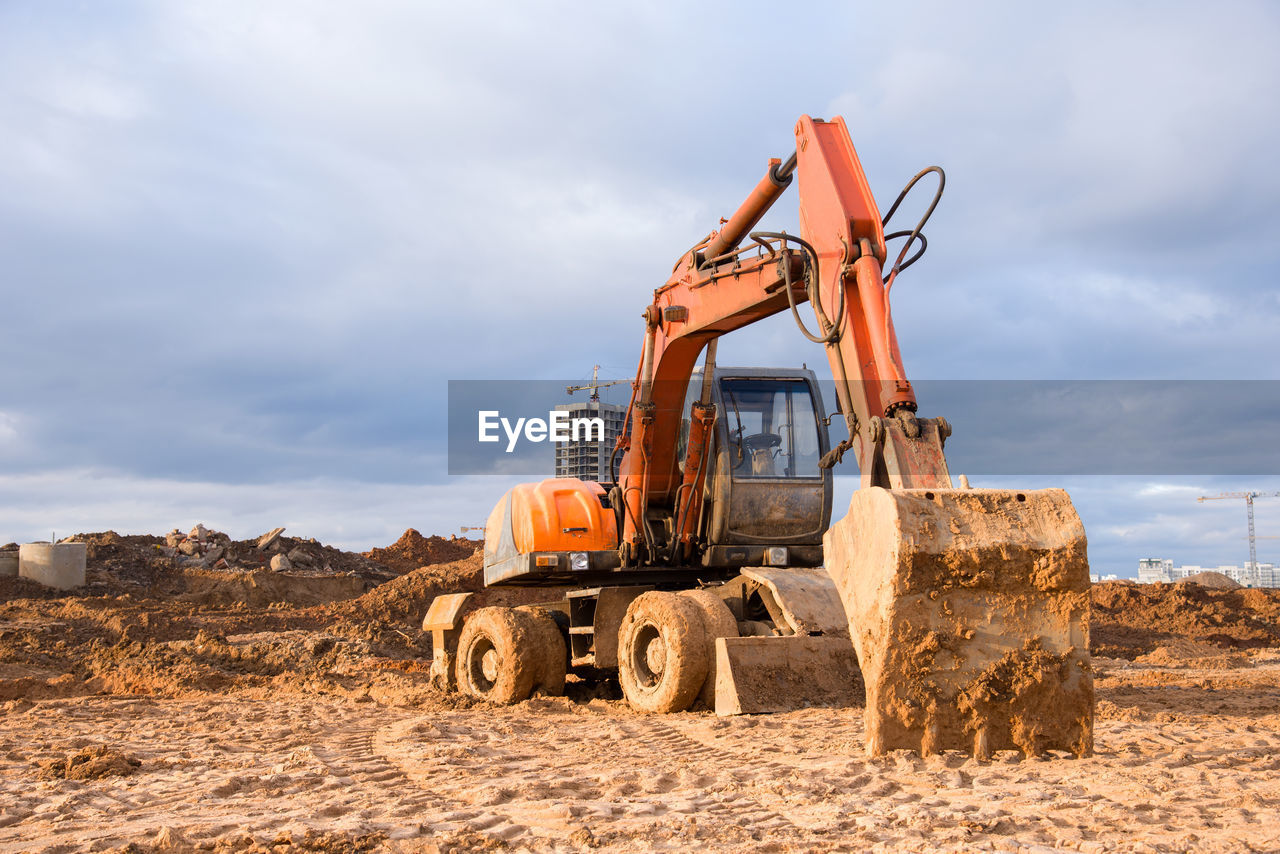 Bucked wheel excavator digs ground at a construction site for installing concrete storm pipes.