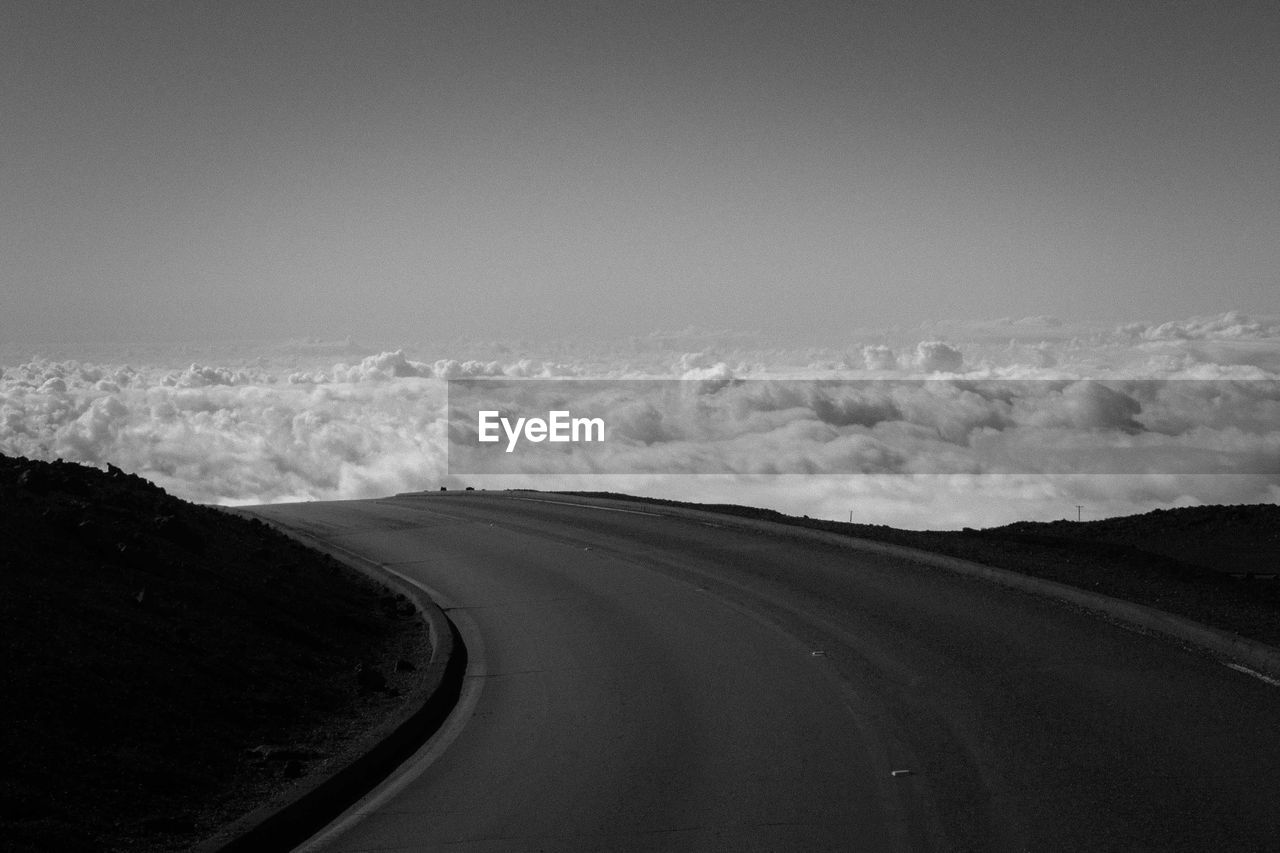 Empty road on mountain leading towards cloudscape