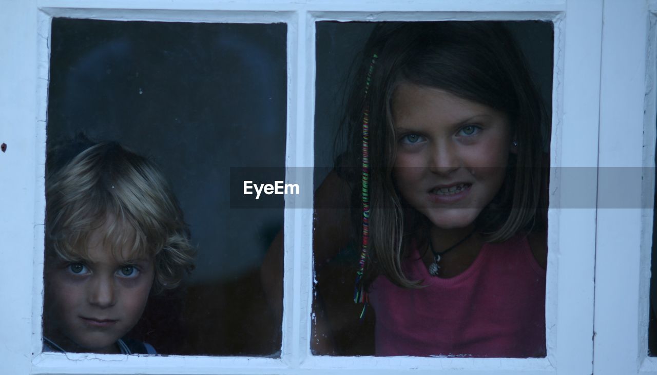 Portrait of sibling seen through window