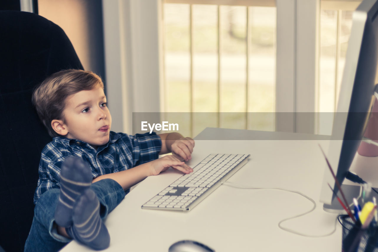 Little boy playing games on a computer at home.