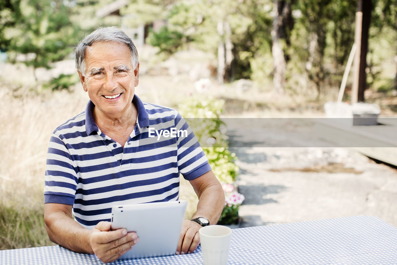 Portrait of smiling mature man with digital tablet