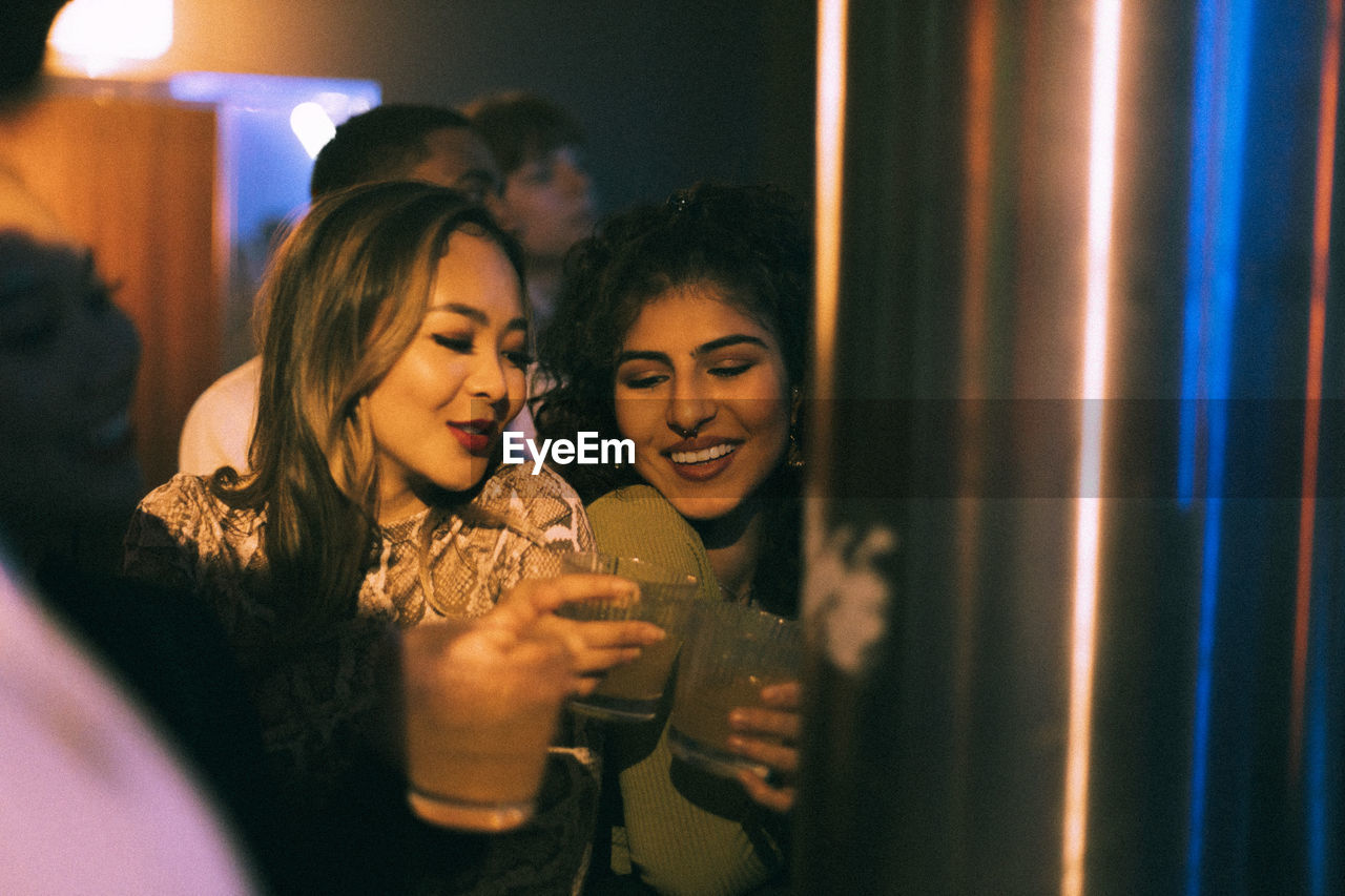 Cheerful young friends with drinks enjoying in club on weekend