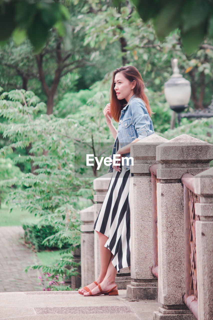 Side view of woman looking away while sitting on footbridge 