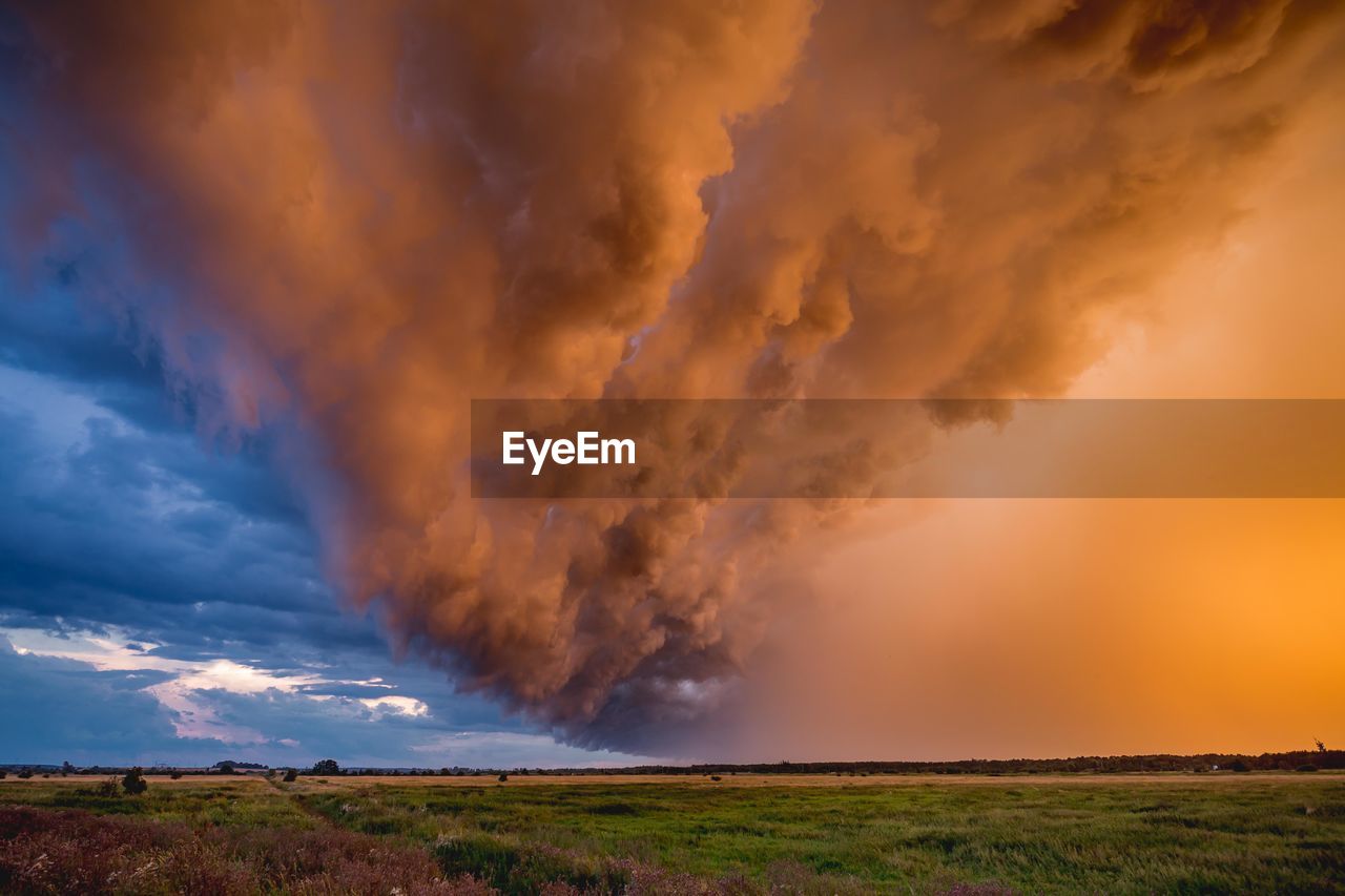 Scenic view of landscape against dramatic sky during sunset