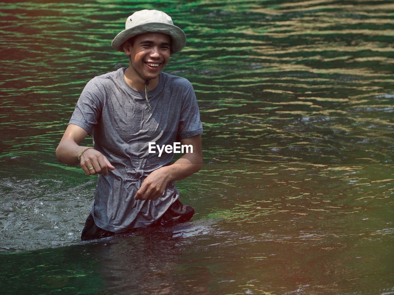 PORTRAIT OF A SMILING YOUNG WOMAN STANDING IN WATER