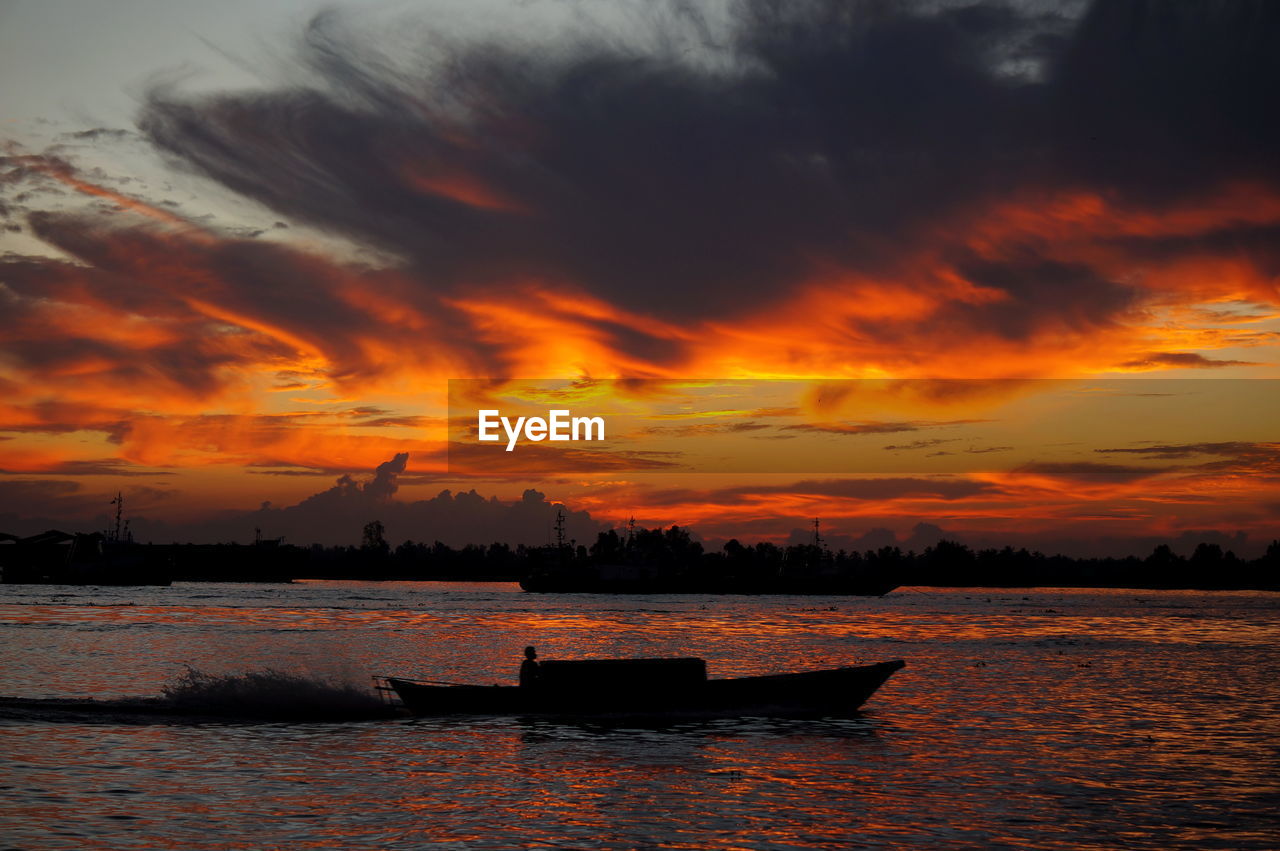 Silhouette boat in sea against sky during sunset