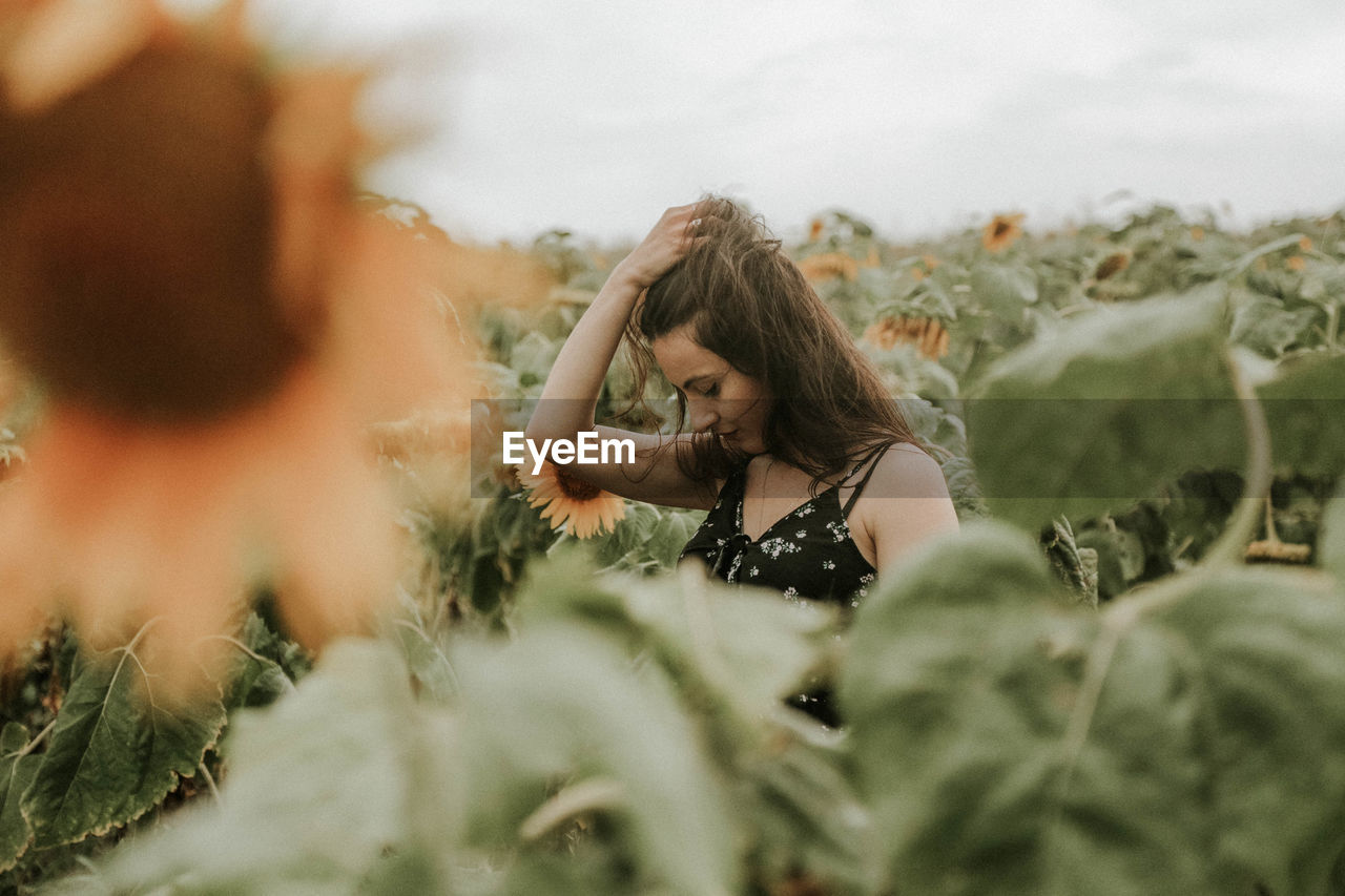 Young woman standing amidst sunflowers on field