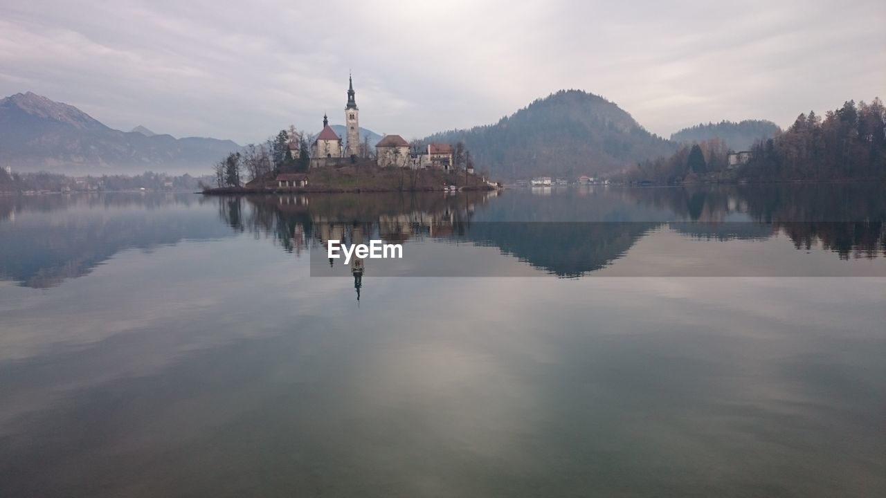 Scenic view of lake bled and church against cloudy sky