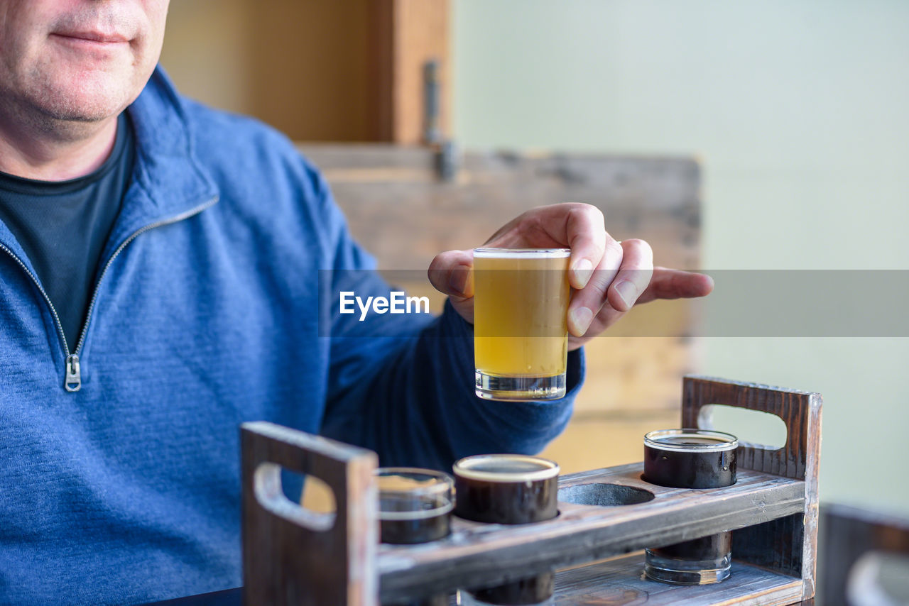 Midsection of man having beer in restaurant