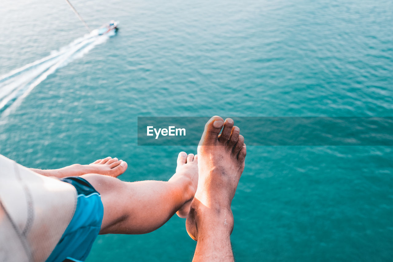 Low section of man and woman paragliding over sea