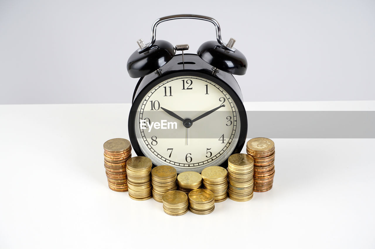 Stack of coins around the alarm clock. business and time management concept