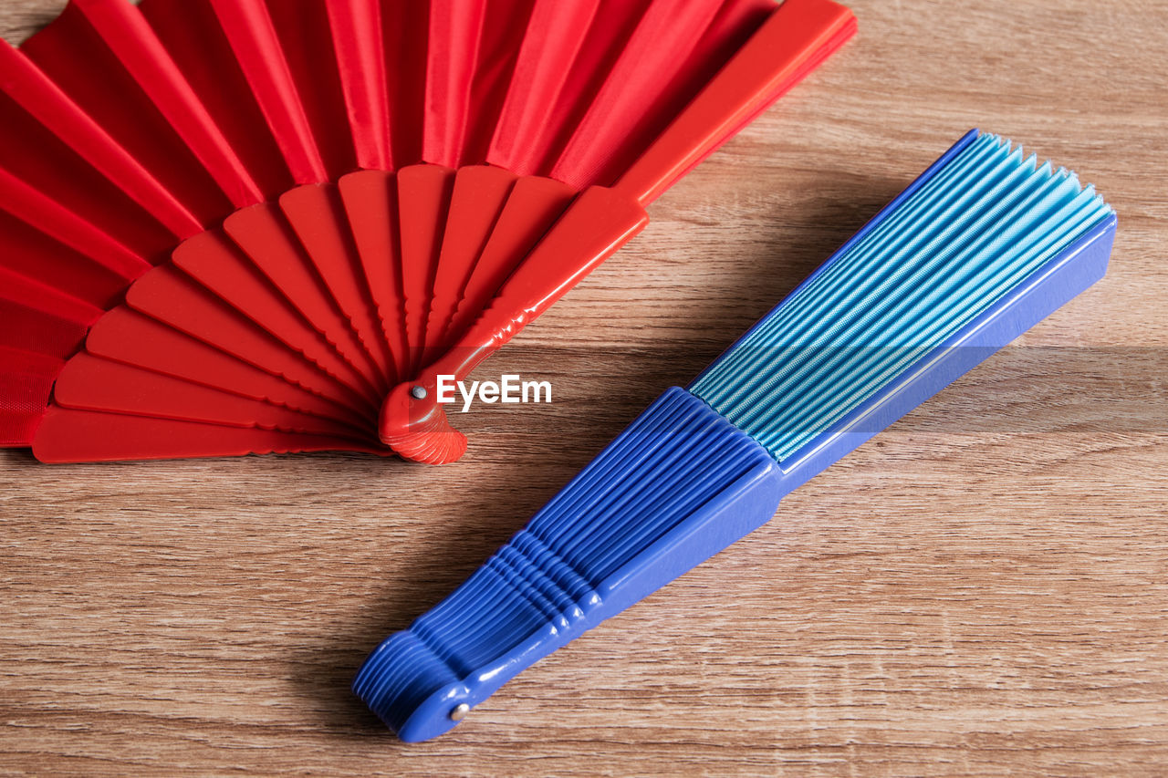 red, wood, indoors, no people, high angle view, blue, table, hand fan, close-up, still life, pattern