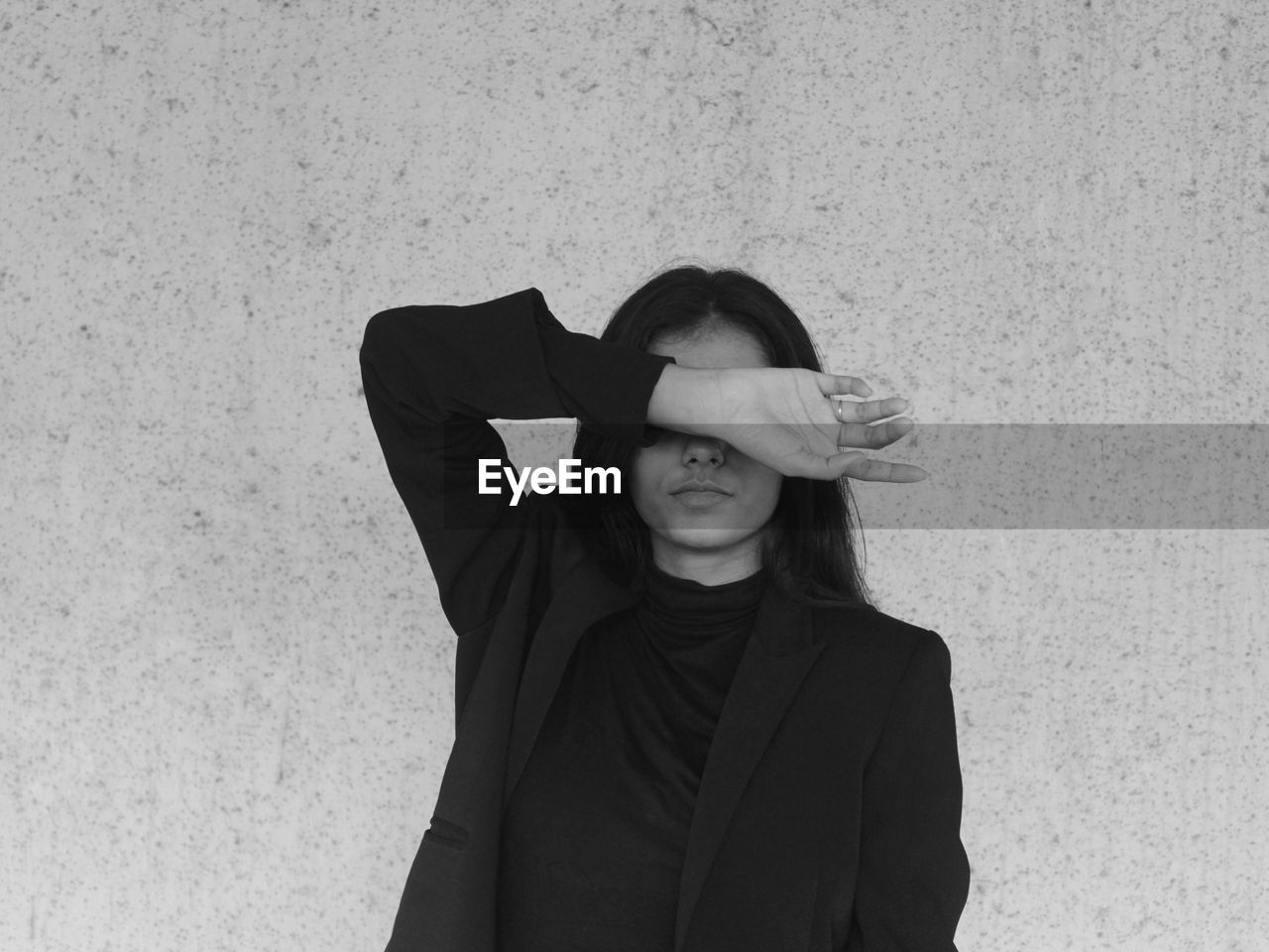 Portrait of a young woman wearing a blazer standing against wall