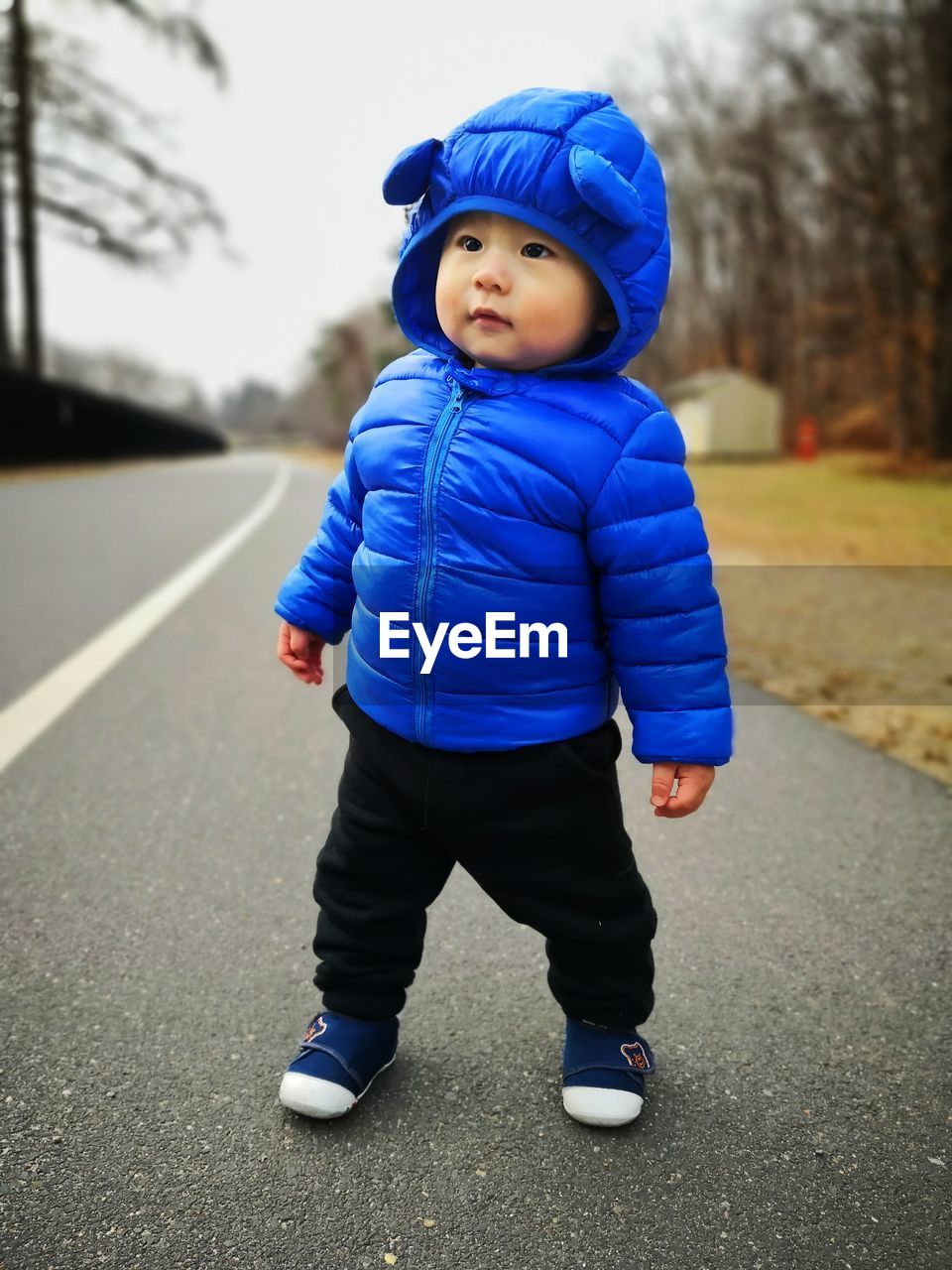 Full length of cute baby boy wearing winter jacket while standing on road