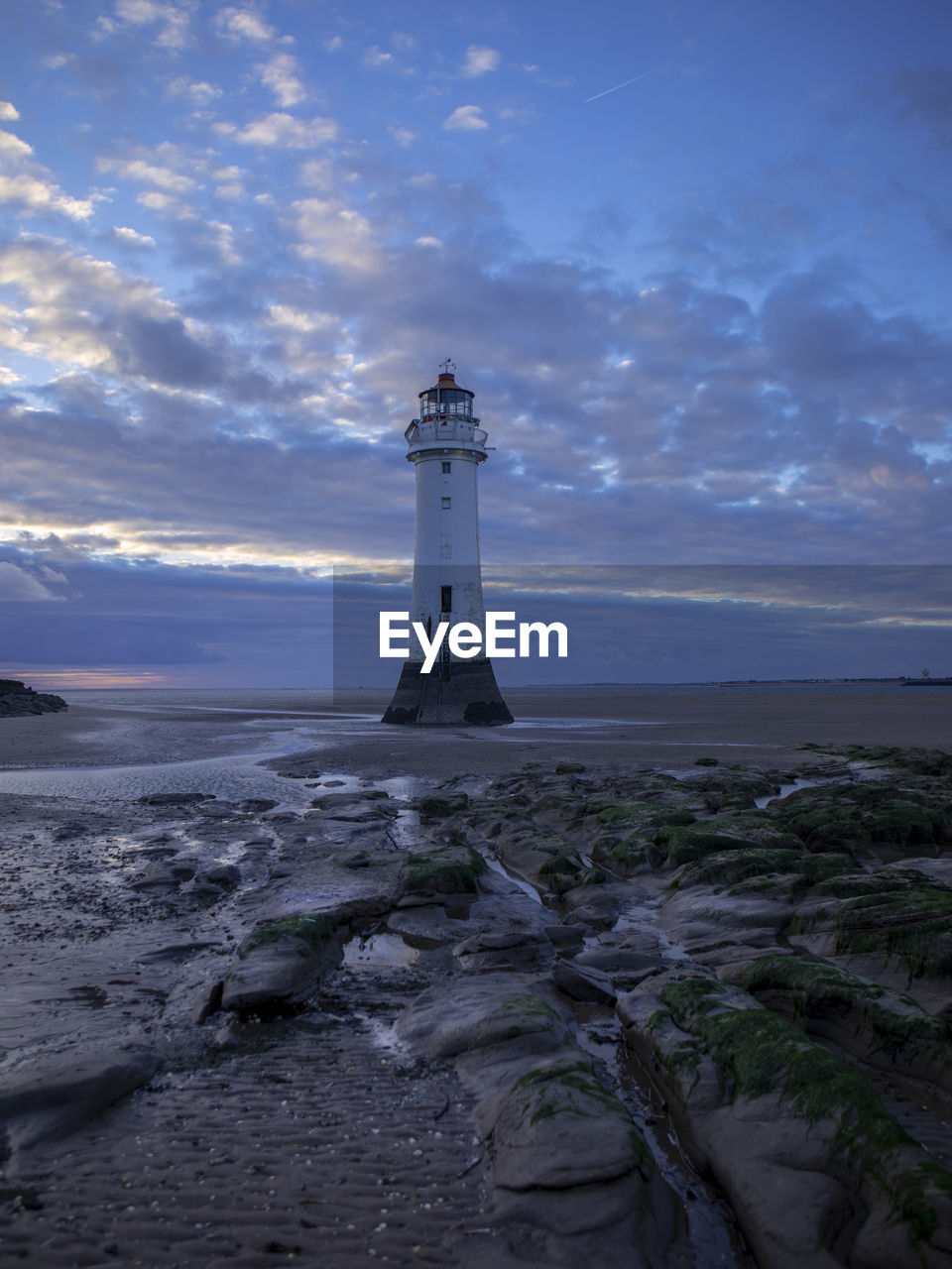 Lighthouse by sea against sky