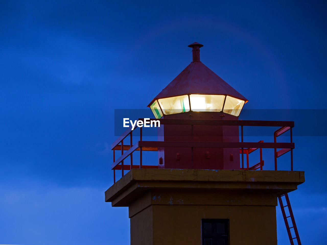 Closeup of the top of an orange lighthouse, iceland