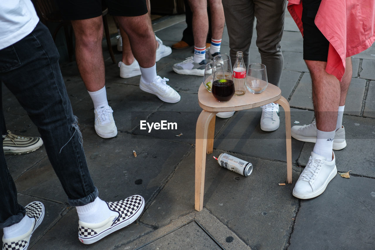 low section, group of people, human leg, shoe, standing, men, adult, footwear, city, limb, human limb, lifestyles, sneakers, day, leisure activity, group, street, high angle view, casual clothing, clothing, medium group of people, outdoors