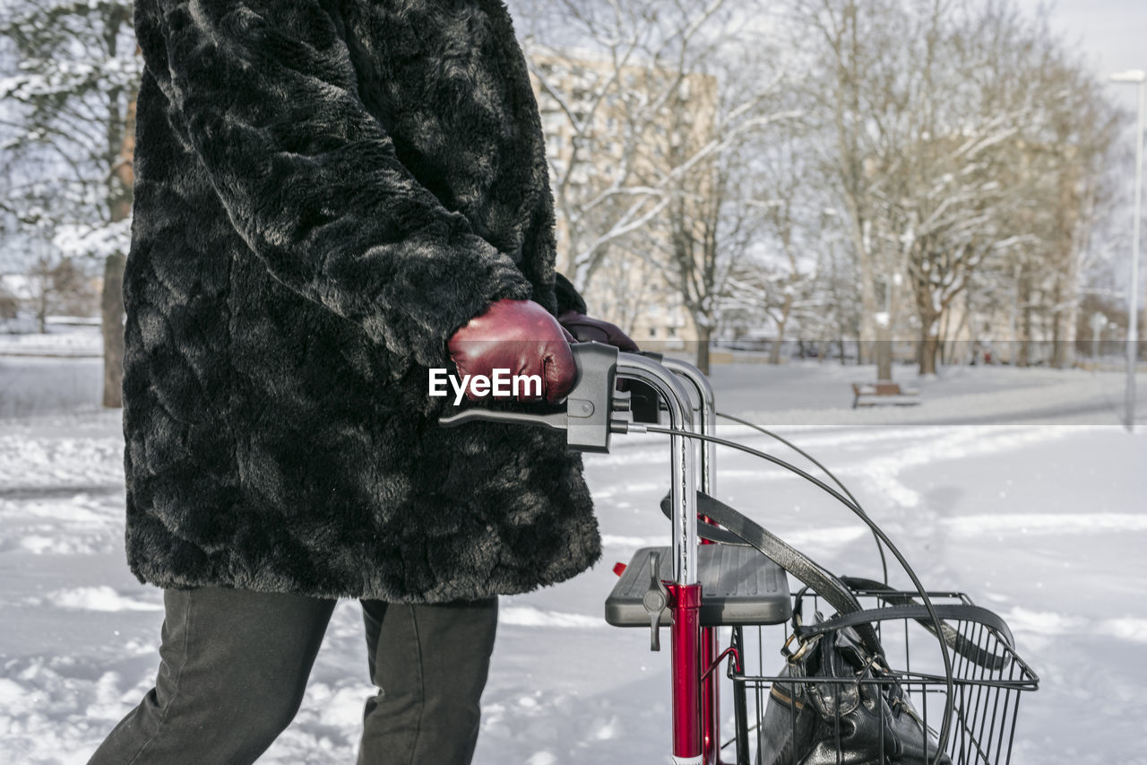 Mid section of senior woman with walking frame during winter walk