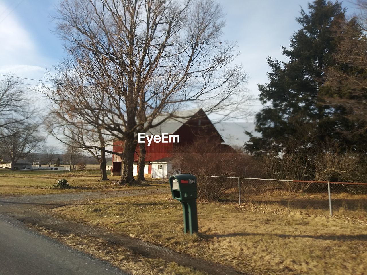 BARE TREE AND HOUSE ON FIELD BY BUILDING AGAINST SKY