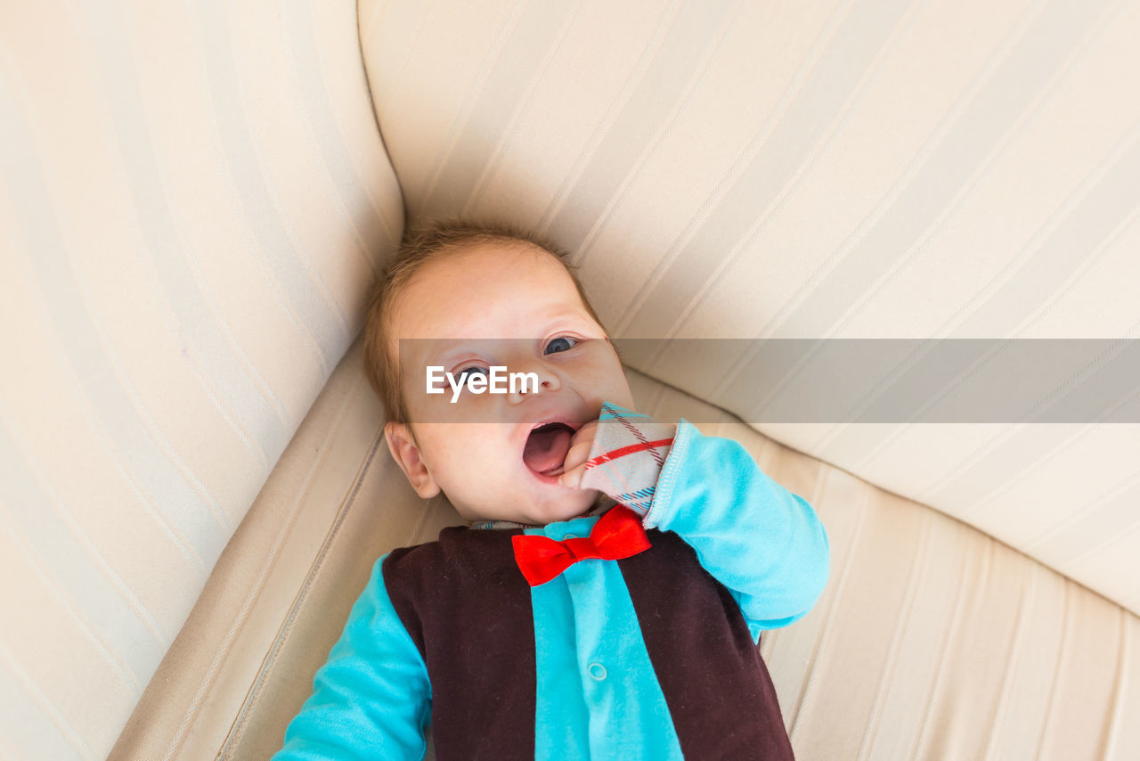 portrait of cute baby boy looking away while standing against wall