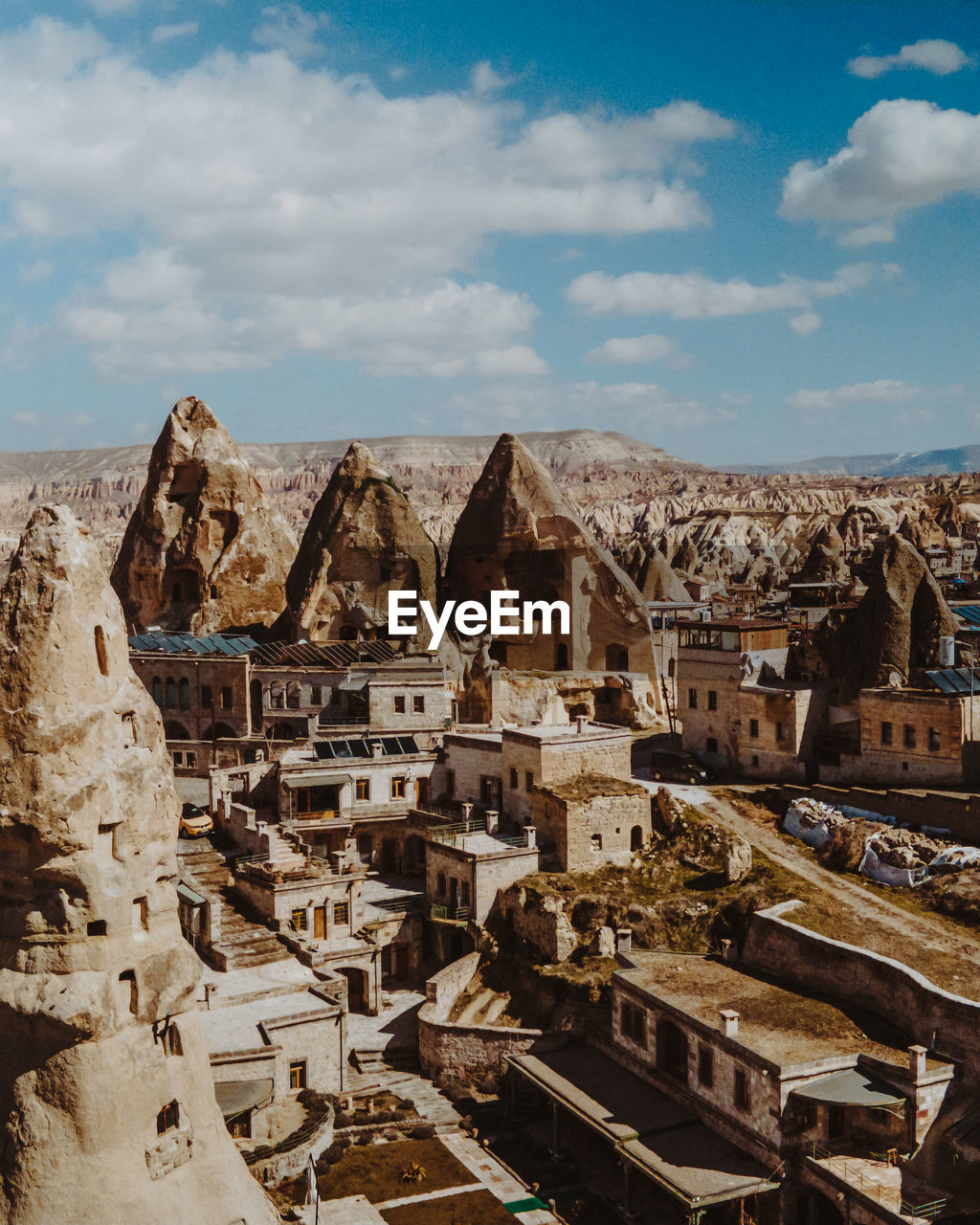 Amazing scenery of massive fairy chimneys and traditional aged houses located in mountainous valley against cloudy blue sky on sunny day in cappadocia turkey