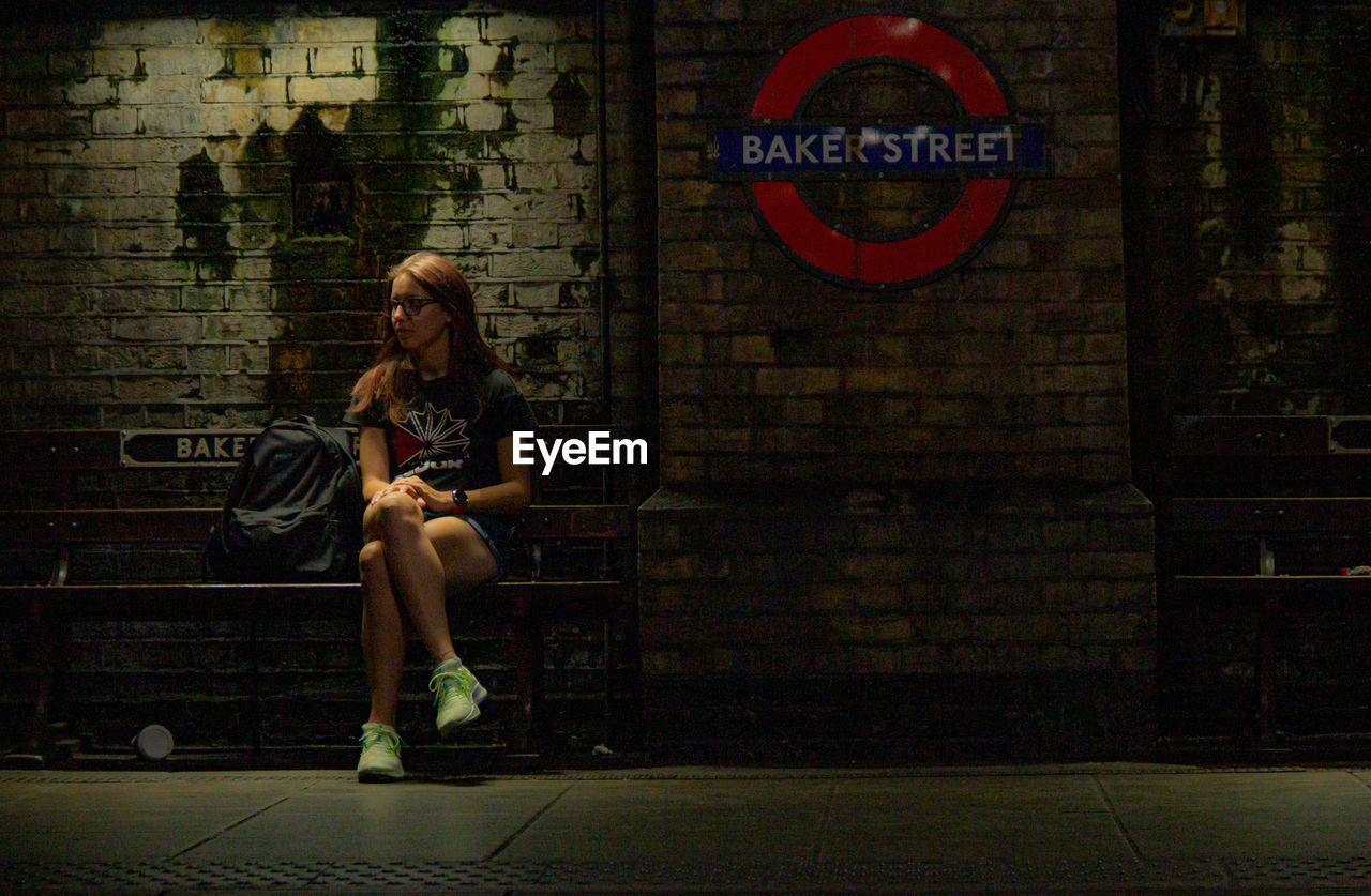 Portrait of young woman sitting on station bench