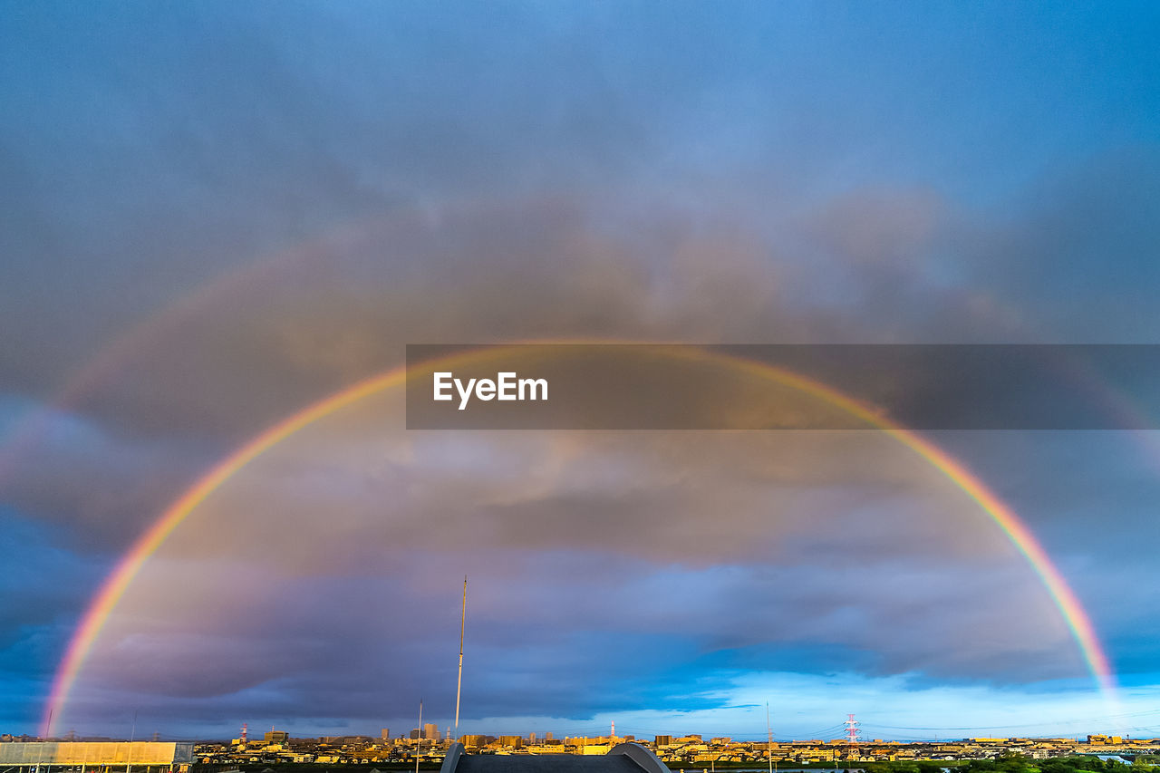 Idyllic shot of rainbow over cityscape against cloudy sky