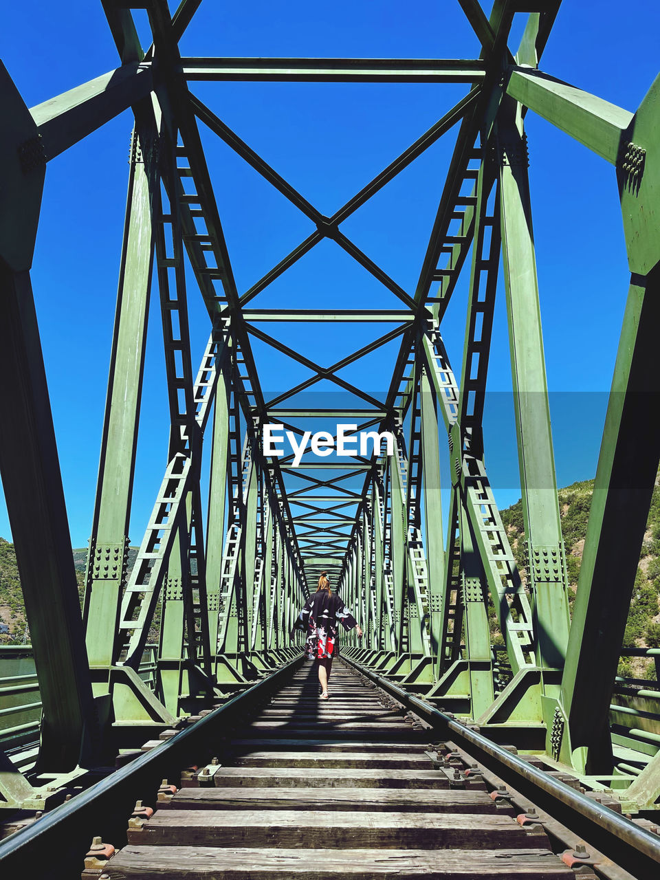 REAR VIEW OF MAN ON FOOTBRIDGE