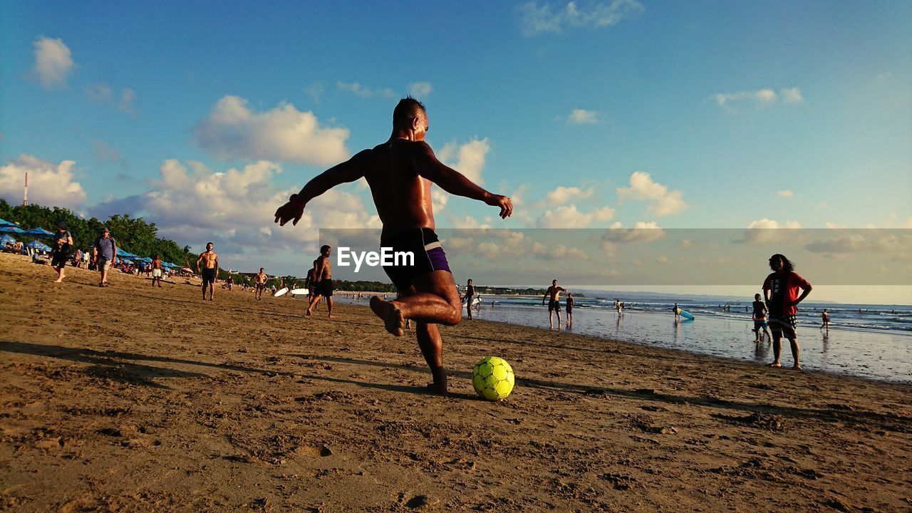 Man playing soccer at beach against sky